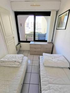 dwa łóżka w pokoju z dużym oknem w obiekcie Résidence TERRASSES DE LA MEDITERRANEE 1 - 2 Pièces pour 4 Personnes 64 w mieście Port Leucate