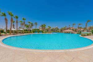 a large swimming pool in a resort with palm trees at VESTA - Sahl Hasheesh Residence in Hurghada