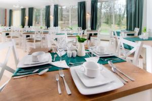 a dining room with a table with white plates and silverware at Marta Medical in Połczyn-Zdrój