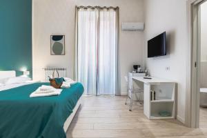 a bedroom with a bed and a desk and a television at RUA DE MAR CHIATAMONE in Naples