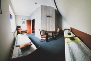 um quarto com duas camas, uma mesa e uma cadeira em Hotel Na Wzgórzu em Gniew