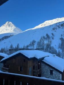 a cabin covered in snow with mountains in the background at Chalet Du Jardin Alpin Ii - 3 Pièces pour 4 Personnes 794 in Val-d'Isère