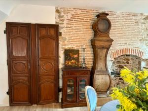 een houten grootvaderklok naast een stenen muur bij Château de la Pervenchère gîte Marin in Casson