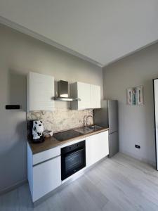 eine Küche mit weißen Schränken und einem schwarzen Gerät in der Unterkunft Brass apartment in Castellammare di Stabia