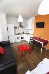 een woonkamer met een rode tafel en een keuken bij Arce apartamentos in Sevilla