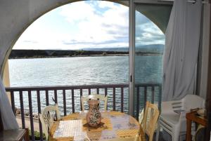una mesa con un jarrón en el balcón con vistas al agua en Résidence LES PORTES DE LA MEDITERRANEE - Studio pour 4 Personnes 14, en Port Leucate