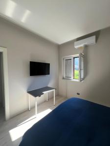 Schlafzimmer mit einem Bett, einem Schreibtisch und einem TV in der Unterkunft Brass apartment in Castellammare di Stabia