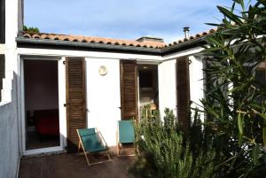 Casa blanca con patio con 2 sillas verdes en Résidence LES CANDEILLERES - Maisons & Villas pour 6 Personnes 94, en Port Leucate