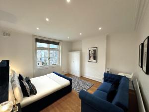 a bedroom with a bed and a blue couch at Captivating 2-Bed Flat in Maida Vale near Abbey Road in London