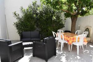 eine Terrasse mit einem Tisch, Stühlen und einem Baum in der Unterkunft Résidence LES PATIOS 1 - Maisons & Villas pour 6 Personnes 924 in Port Leucate