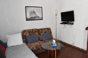 ein Wohnzimmer mit einem Sofa und einem TV in der Unterkunft Résidence LES PATIOS 1 - Maisons & Villas pour 6 Personnes 924 in Port Leucate