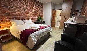 1 dormitorio con cama y pared de ladrillo en Village Lodge Harrismith, en Harrismith