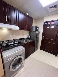 a kitchen with a stove and a washing machine at Fully furnished studio apartment in Ajman 