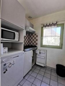 una cocina con electrodomésticos blancos y una ventana en Résidence Ile Des Pecheurs - Maisons & Villas pour 6 Personnes 114, en Port Leucate