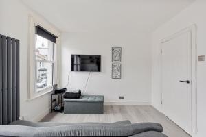 a white living room with a couch and a tv at Stylish 2-Bedroom Flat in Walthamstow in London
