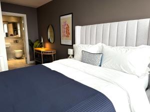 una camera da letto con un grande letto bianco con una coperta blu di Lusso by Luisa - 2 Bed Modern Luxury Apartment in Central Birmingham (5*) a Birmingham