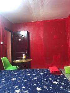um quarto com uma cama, uma mesa e paredes vermelhas em The Big Boss Indian & Nepali Restaurant house em Sihanoukville