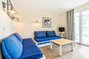ein Wohnzimmer mit einem blauen Sofa und einem Tisch in der Unterkunft Résidence Cap Azur - maeva Home - Appartement 3 Pièces 7 Personnes - Confor 80 in Fouesnant
