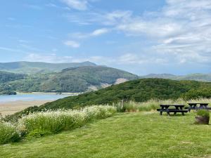 2 Picknicktische auf einem Hügel mit Meerblick in der Unterkunft Empress En Suite Wagon in Arthog