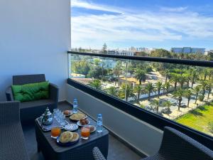een balkon met een tafel met eten en uitzicht op de stad bij luxe appartement met zeezicht en zwembad Mohammedia Parc in Mohammedia