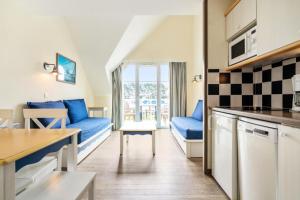 a kitchen and a living room with blue couches and a table at Résidence Cap Azur - maeva Home - Appartement 2 Pièces 5 Personnes - Confort MAE-4387 in Fouesnant