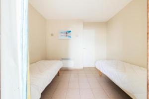 two beds in a room with white walls at Résidence Les Rivages de Rochelongue - maeva Home - Appartement 3 pièces 6 11 in Cap d'Agde