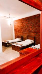 2 camas en una habitación con una pared de ladrillo en City Hostel Colombo Airport, en Katunayake