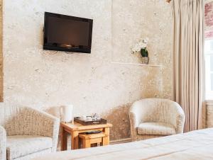 a bedroom with two chairs and a television on the wall at Three Salmons Hotel in Usk