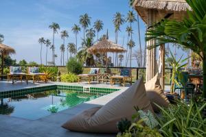 a resort pool with chairs and tables and palm trees at Manao Seaview Pool Villa 32 - 5 Mins Walk To The Beach in Ko Lanta +32 photos