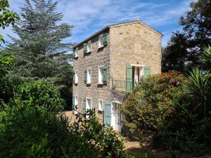 een stenen huis met een balkon ernaast bij MAISON DE CARACTERE AVEC PISCINE in Sartène