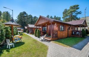 a wooden cabin with a table and chairs in a yard at Domki Hawana in Dąbki