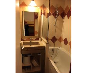 een badkamer met een wastafel, een bad en een spiegel bij Résidence Les Fontaines Blanches - maeva Home - Studio 4 personnes Confort 99 in Morzine