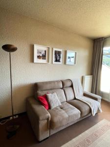 a living room with a brown couch with a red pillow at Résidence Les Glovettes - Studio pour 4 Personnes 164 in Villard-de-Lans