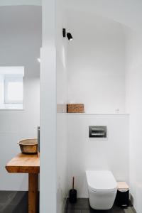 a white bathroom with a toilet and a wooden table at Quinta do Louredo - Évora in Évora