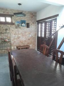 a large wooden table in a room with a brick wall at Casa Charmosa Verde-Azul in Paracuru