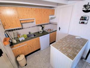 uma pequena cozinha com armários de madeira e um lavatório em Résidence Maisons Des Sables - Pièces 564 em Leucate