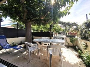einen Tisch und Stühle auf einer Terrasse unter einem Baum in der Unterkunft Résidence Les Nautiques Du Golf - Maisons & Villas pour 6 Personnes 494 in Leucate