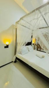 1 dormitorio con 1 cama blanca con dosel en alovera inn, en Weligama