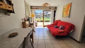 uma sala de estar com um sofá vermelho e uma mesa em Résidence Queyrettes - 2 Pièces pour 4 Personnes 134 em Puy-Saint-Vincent