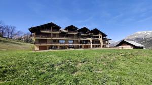 a large building on top of a grassy hill at Résidence Queyrettes - 2 Pièces pour 4 Personnes 134 in Puy-Saint-Vincent