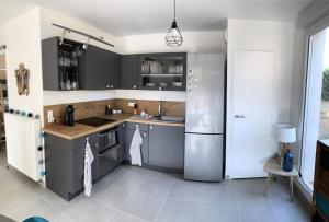 cocina con armarios grises y nevera de acero inoxidable en Résidence Villa Naka - 2 Pièces pour 4 Personnes 634, en Six-Fours-les-Plages
