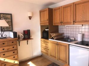 a kitchen with wooden cabinets and a counter top at Résidence Les Charmettes - Studio pour 2 Personnes 304 in Arc 1600