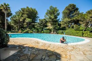 a woman sitting in front of a swimming pool at Résidence La Pinède - maeva Home - Studio 4 Personnes - Sélection MAE-7619 in Hyères +12 photos