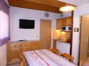 a kitchen with a table and a tv on the wall at Résidence Combettes - 3 Pièces pour 5 Personnes 324 in Les Contamines-Montjoie
