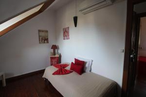 a bedroom with a bed with red pillows on it at Casas da Biquinha in Sintra