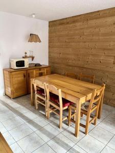 uma cozinha com uma mesa de madeira com cadeiras e um micro-ondas em Résidence Prapelier - Studio pour 4 Personnes 774 em Vénosc