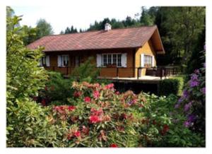 a house with a lot of flowers in front of it at Chalet au bord de l’eau in Saint-Quirin