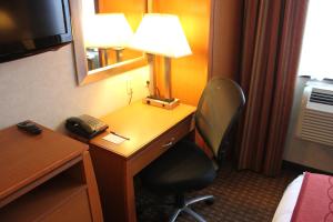 a hotel room with a desk with a lamp and a chair at Bellerose Inn in Queens