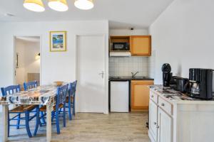 een keuken met een tafel en blauwe stoelen in een kamer bij Résidence Debussy - maeva Home - Appartement 2 Pièces 4 Personnes - Budget 37 in Carnoux
