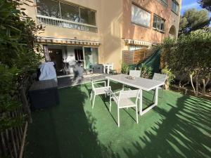 una mesa blanca y sillas en un césped frente a un edificio en Résidence Pinedes Aryana - 4 Pièces pour 6 Personnes 754, en Six-Fours-les-Plages